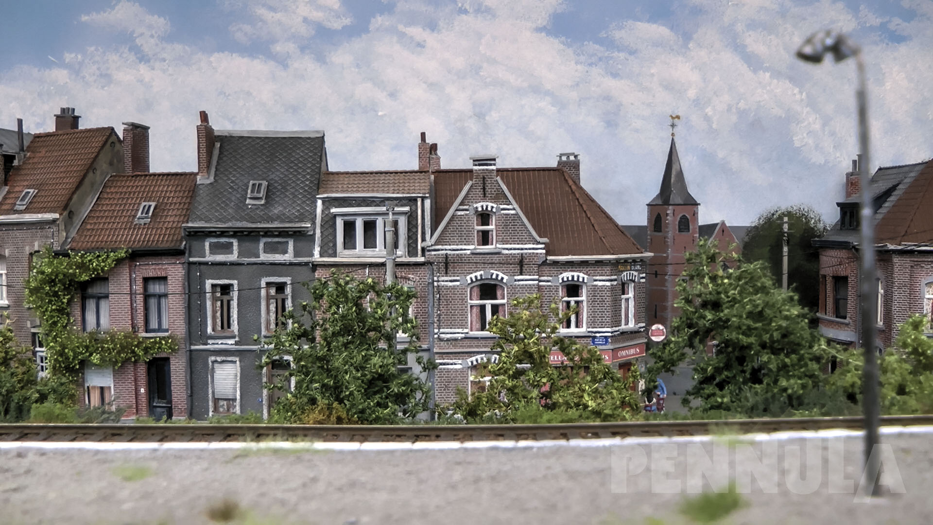 So liegt der Schwerpunkt der Modellanlage auf einer perfekt gestalteten Häuser- und Landschaftskulisse sowie auf einem einfachen Gleisplan auf dem Dieselzüge verkehren, die typisch für die belgischen Eisenbahnen der 1980‘er Jahre waren.